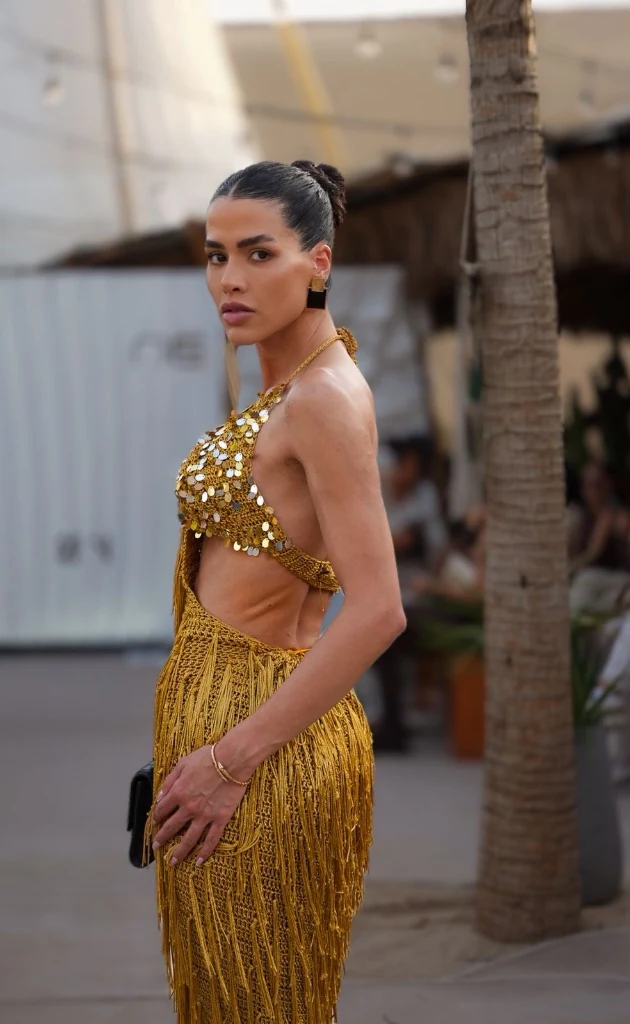 Modelo de vestido dourado com franjas e costas abertas